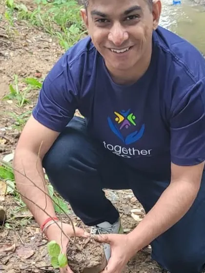 A happy volunteer from NTT Data holds a native sapling, ready to plant it along the banks of the creek to help with flood management.