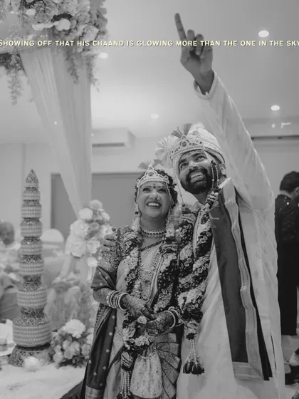 A joyful black and white photo of the groom pointing to the sky, as if showing off his bride. A candid moment full of pride and happiness.