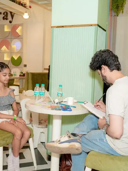 A caricature artist at work, sketching a portrait of a young guest during a party.