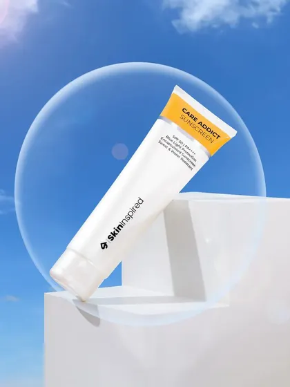 A conceptual studio shot for Skininspired sunscreen. The product is placed on white geometric blocks against a sky backdrop, with a clear orb adding a futuristic and scientific feel.