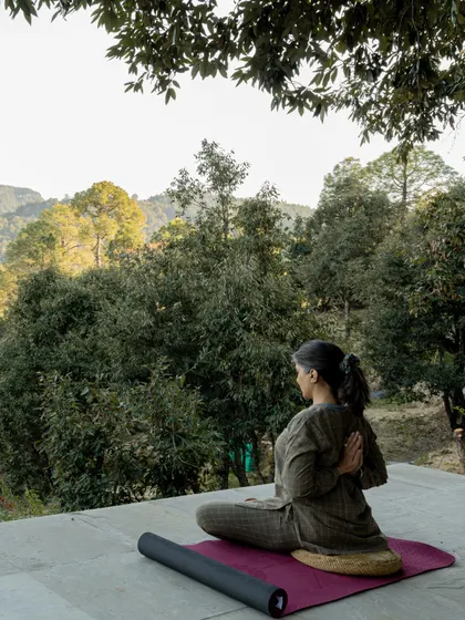 Seated in a preparatory pose for meditation on an outdoor platform. My retreats provide the perfect setting to deepen your practice, surrounded by the tranquility of the forest.