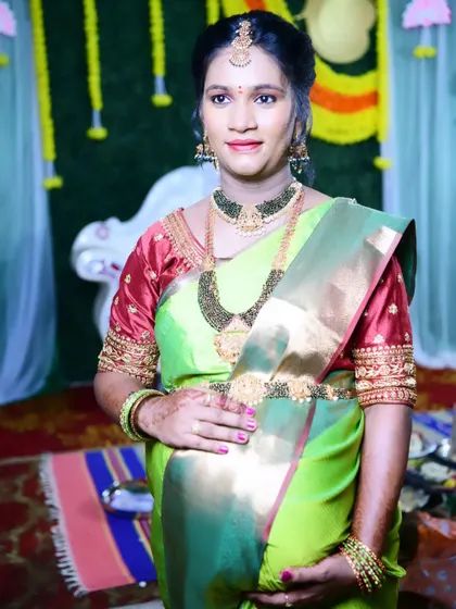 A full portrait of Sonu at her baby shower. The makeup is balanced to complement her vibrant green and red saree and heavy jewellery.