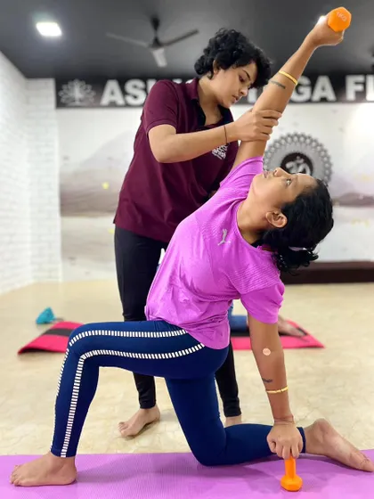 Incorporating light weights adds a strength-building element. Here, an instructor helps a student maintain correct form in a weighted side lunge stretch.