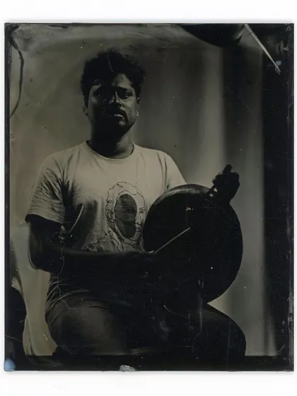 A musician and his handpan captured on a 4x5 inch glass plate. The wet plate process beautifully renders the textures of the instrument and the artist's focused expression.