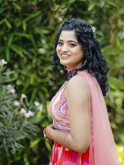 A side profile of the bride, smiling and looking radiant. The makeup is natural and enhances her happy glow.