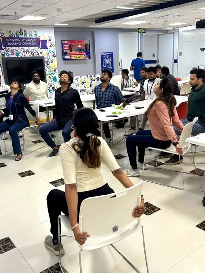 Participants practicing a gentle backbend while seated, helping to open the chest and improve posture.
