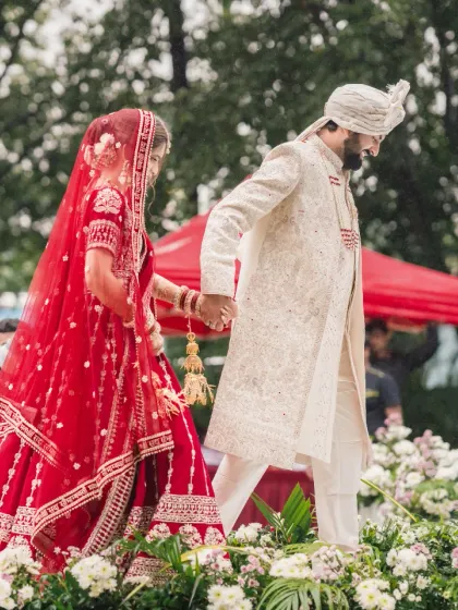 The couple walks hand-in-hand down an aisle lined with flowers, a beautiful start to their journey together.