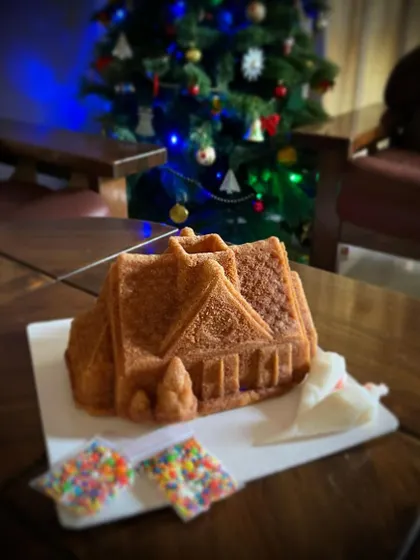 My decorate-your-own Christmas Cottage cake, sitting pretty by the tree. This kit is all about providing a fun, festive activity for the family without any of the stress.