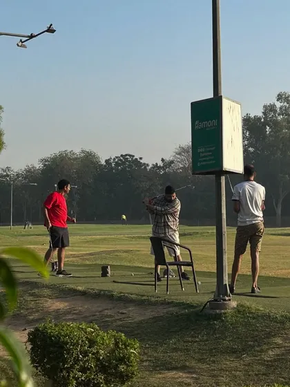 A view of the range from a distance, showing three golfers practicing near our Hamoni sign.