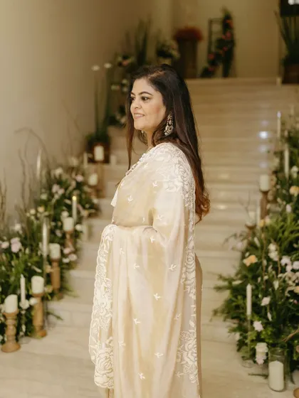 A candid shot capturing the joy of the celebration. The soft lighting and floral decor in the background create a warm and elegant atmosphere.