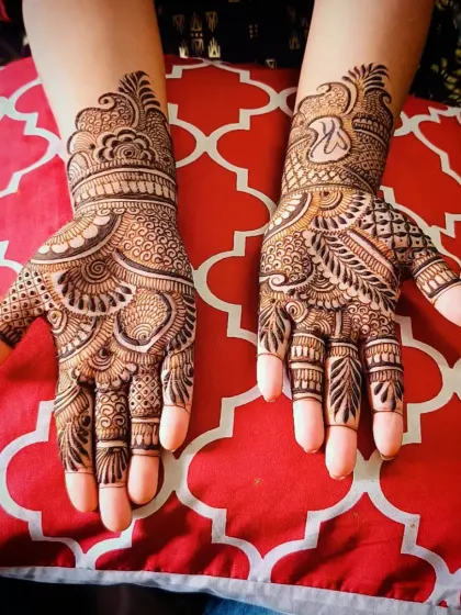 A top-down view of the 'K' initial mehandi against a bright background.