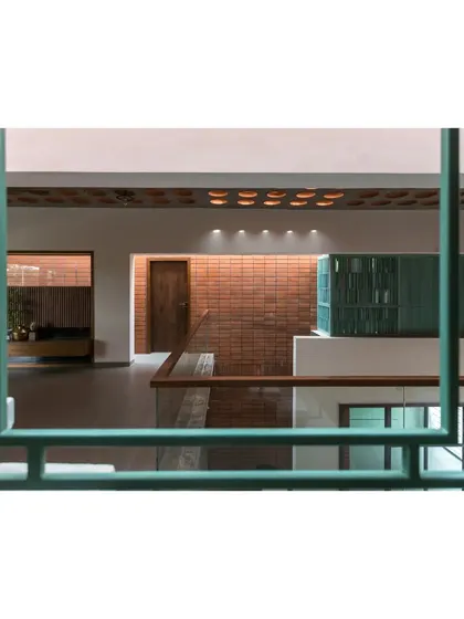 A detail from 'An Earthy Affair' showing the view through a vibrant green railing. This element adds a splash of color and serves as a framing device, offering curated glimpses into the different levels and spaces within the home.