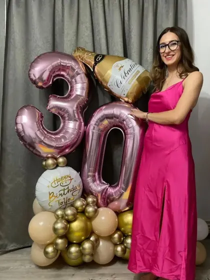 A custom balloon bouquet makes for a great birthday gift and photo prop. This arrangement includes number foils, a champagne bottle balloon, and a personalized tag for the birthday girl.