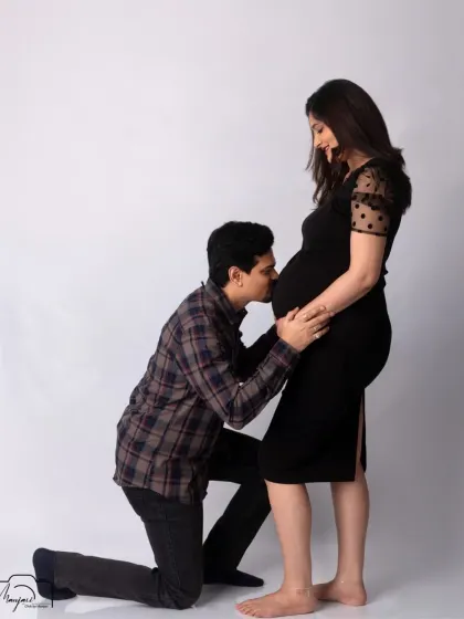 A classic and tender bump kiss. The simple black dress and white background create a clean, modern, and timeless look.