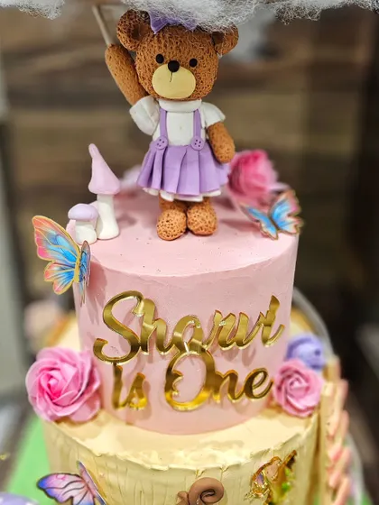 A close-up of the cute teddy bear figurine on the fairy cake.