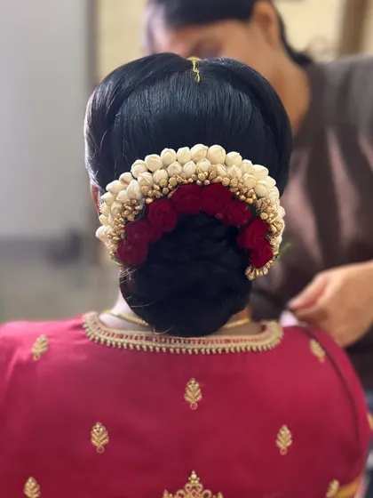 A traditional neat bun completely encircled by a gajra of jasmine and red flowers. This is a very popular choice for ceremonies and looks beautiful with traditional attire.
