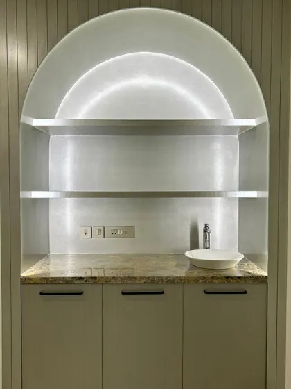As part of a luxury residence, we designed this integrated home salon counter. The arched niche with built-in shelving and lighting creates a stylish and functional space for personal grooming.