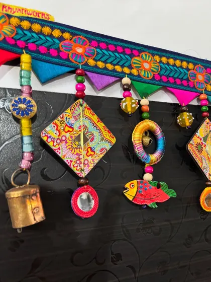 A closer look at the details of 'The Summer Song' Toran. The embroidered floral topper and colorful felt triangles create a beautiful frame for the hanging elements.