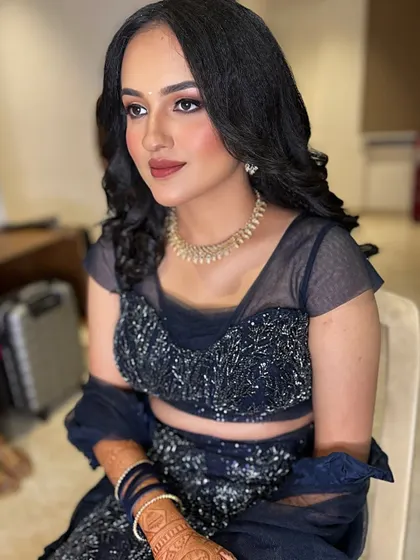 An elegant and modern reception look featuring a navy blue lehenga. The makeup is soft and glamorous with a neutral lip, paired with crimped waves for a chic hairstyle.