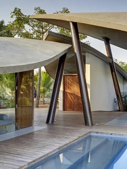 For 'The Leaf House', a weekend retreat, the form of the building itself was inspired by nature. The organic, leaf-shaped concrete shells shelter the living spaces while opening up to the landscape, creating a home that feels like a natural extension of its environment.