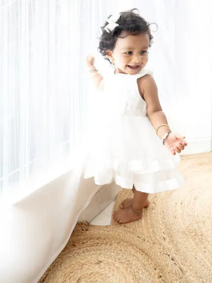 A sweet, candid shot of the baby girl exploring by the window, with the light creating a beautiful glow.