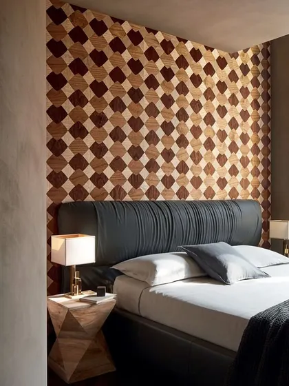 A bedroom with a stunning accent wall of wood marquetry wallpaper. The checkerboard pattern, crafted from different wood tones, adds warmth, texture, and a sophisticated geometric element to the space.