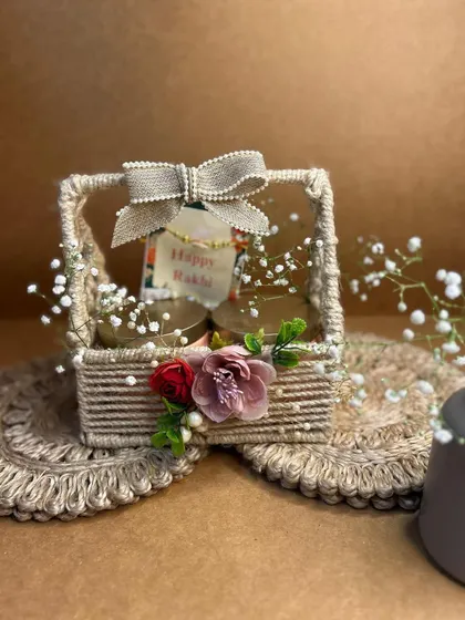 A rustic and charming Rakhi gift basket. This small jute basket is simply decorated with flowers and a bow, perfect for a small, heartfelt gift.