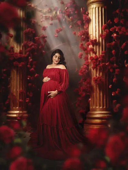In my studio, we can create bold and moody portraits. Here, a beautiful mom to be is surrounded by red roses and dramatic lighting, creating a powerful and romantic image of motherhood.