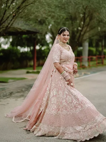 The bride, radiant in her pink lehenga, gives a joyful twirl. A perfect bridal portrait full of life and happiness.