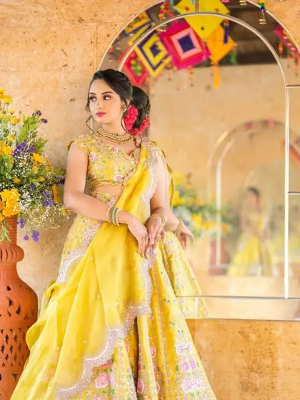 A stunning Haldi look. The bride's yellow lehenga and floral hair accessory are paired with a makeup look that is both vibrant and elegant.