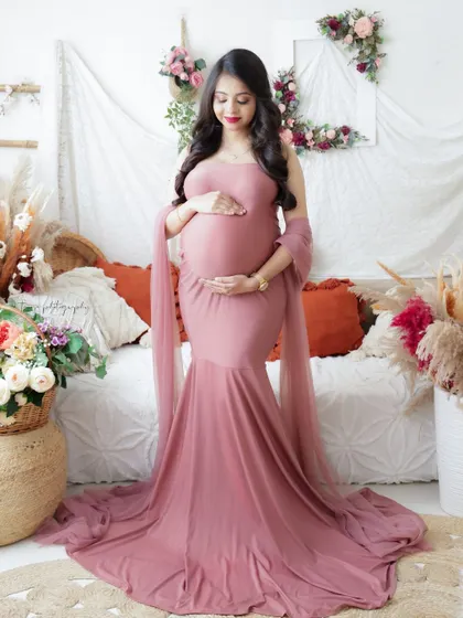 A duplicate of image 201, this serene portrait in a boho-chic setting features a mom-to-be in a dusty pink gown holding a bouquet of roses.