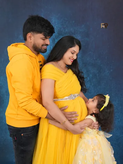 A picture of pure family joy. The older daughter hugs her mom's baby bump, sharing in the excitement. The coordinated yellow outfits make this a bright and happy family portrait.