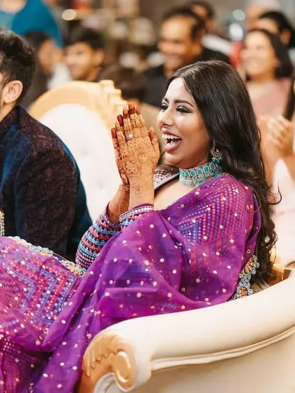 The couple enjoying a performance during their sangeet, their faces lit up with laughter. Capturing audience reactions is part of telling the full story.