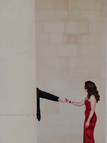 A creative portrait in Malta, with the groom's hand reaching out from behind a pillar to hold the bride's, symbolizing connection and trust.