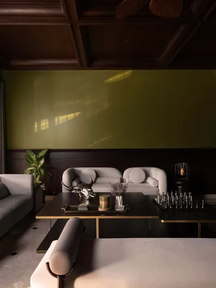 This view shows the overall composition of the living room, with its clean lines, balanced furniture arrangement, and the dramatic effect of the high, dark ceiling. It's a space designed for timeless elegance.