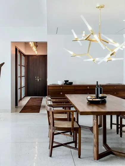 This open-plan dining and living area in the Terrazzo Residence showcases our minimalist approach. The space is defined by a few carefully chosen pieces, like the indoor swing and a modern brass chandelier, which add character without creating clutter.