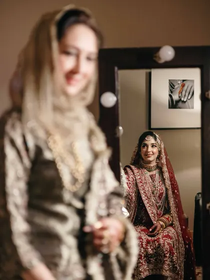 An artistic shot of the bride looking in the mirror while her mother looks on. This creative composition speaks of reflections, generations, and a mother's pride.