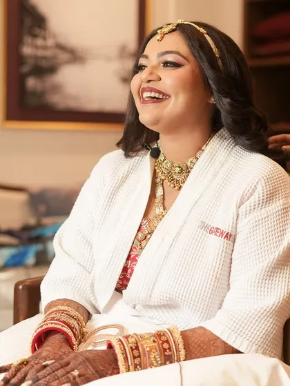 The getting-ready process is a cherished part of the wedding day. Here, the hairstylist adds the final curls while the bride, already radiant in her jewellery, anticipates the full transformation.