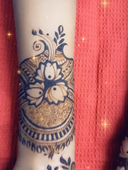 A close-up of a designer mehendi cuff, featuring lotuses and peacocks in a modern, graphic style.