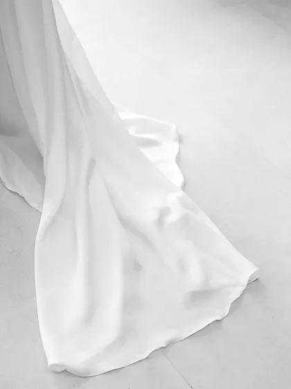 A minimalist black and white detail shot of the fabric of Khushali's flowing white dress.