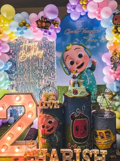 A grand Cocomelon party for Charish's second birthday, this setup includes a shimmering sequin wall, a large light-up number '2', and plenty of colorful balloons and characters.