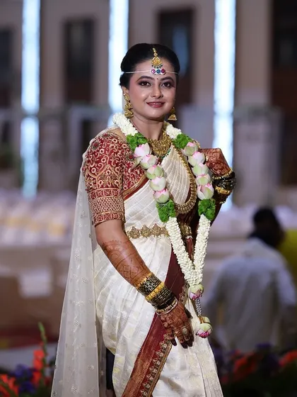 A full portrait of the bride, looking radiant. The dark mehendi on her hands is an essential part of her stunning bridal ensemble.