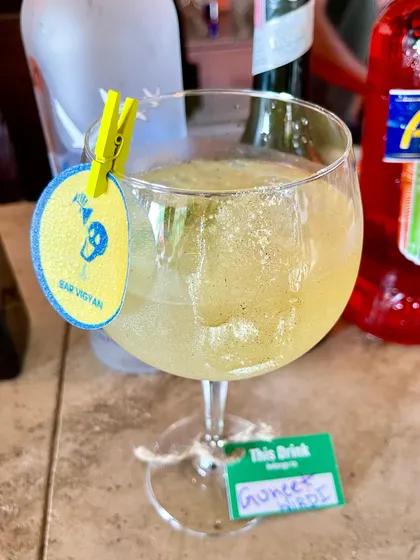 A sparkling cocktail with edible glitter, served with a personalized tag for a guest. This is a great way to make guests feel special at weddings or birthdays.