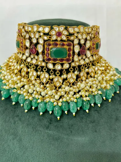 A detailed view of a bridal choker with green beads and pearl detailing. This rental piece is perfect for a traditional bride.