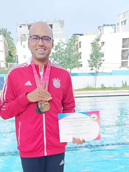 An athlete proudly wearing his medals from the State Masters Championships. Our program helps adult swimmers reach their peak competitive performance.