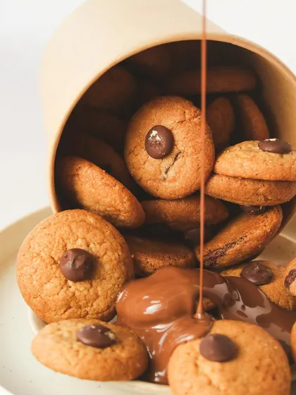 Indulge in the ultimate treat: warm chocolate chip cookies being drizzled with rich, melted milk chocolate.