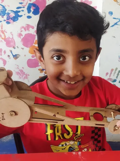 A big smile from a proud builder and his newly assembled rubber-powered car.