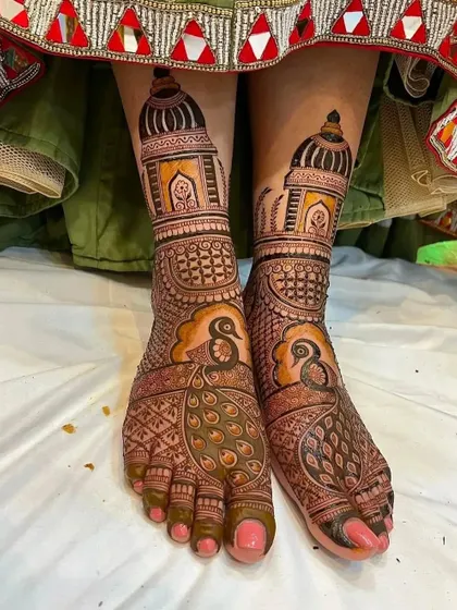 A beautiful bridal foot design with large peacock figures on the top of the feet and palace architecture on the ankles. This perfectly complements a Rajasthani-style bridal look.