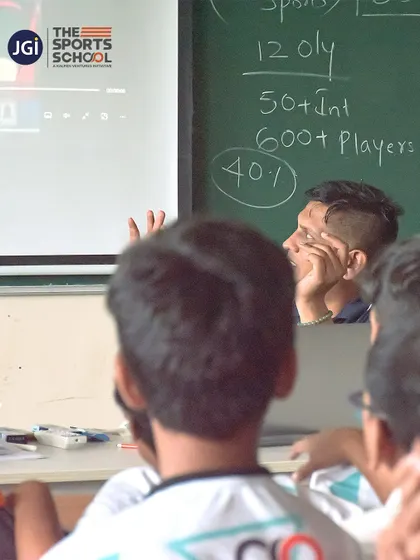 A student listens intently as a coach explains complex game statistics written on the blackboard.