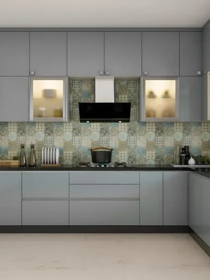 A sleek, grey L-shaped kitchen featuring built-in appliances for a streamlined finish. I used frosted glass cabinets with internal lighting to break up the solid color and provide display storage, while the patterned backsplash adds subtle texture.